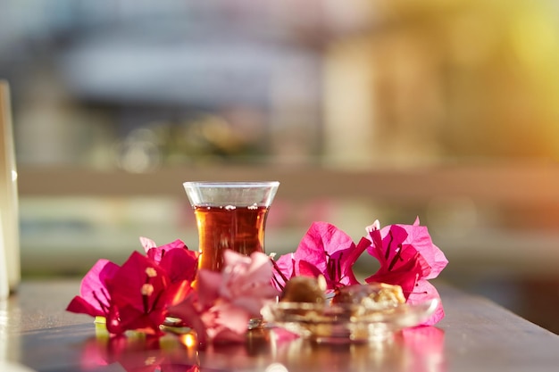 Turkish delight and traditional glass of turkish tea with bougainvillea flowers Romantic dinner concept Relaxing calming drink Travel Turkey concept Bright relaxing drink