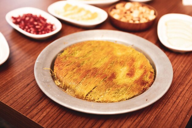 Turkish dessert kunefe kunafa kadayif with pistachio powder and cheese hot eaten a sweet