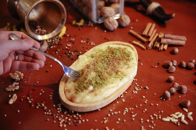 Turkish dessert kunefe, kunafa, kadayif with pistachio powder and cheese hot eaten a sweet