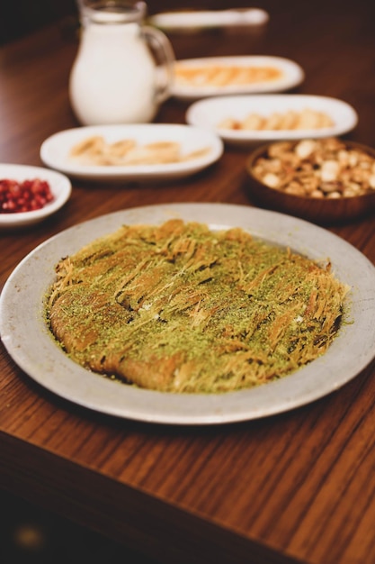 Turkish dessert kunefe, kunafa, kadayif with pistachio powder and cheese hot eaten a sweet