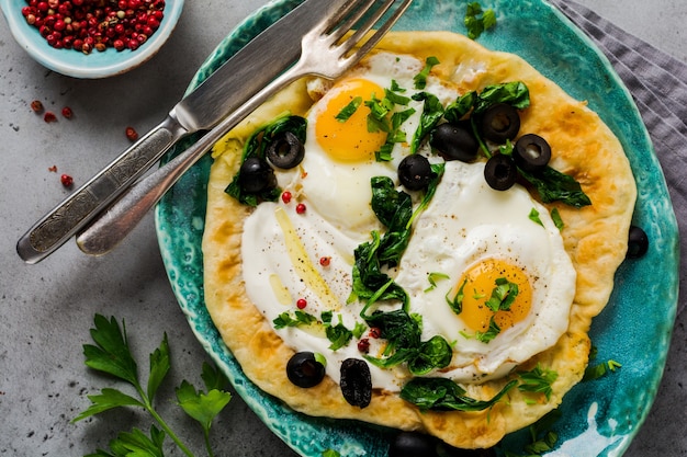 Turkish eggs flatbread with yoghurt, cheese, olives, spinach and red pepper