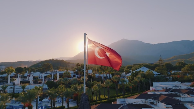 Turkish flag at sunset against the backdrop of the hotel Swimming pool and palm trees Mountain