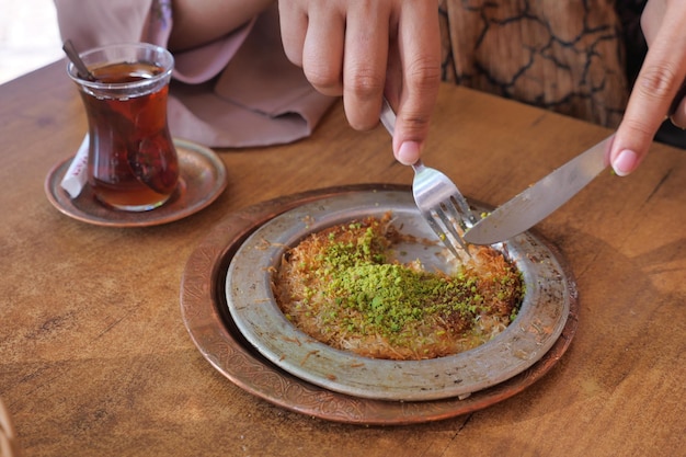 Turkish kunefe dessert in special serving dish with green pistachio