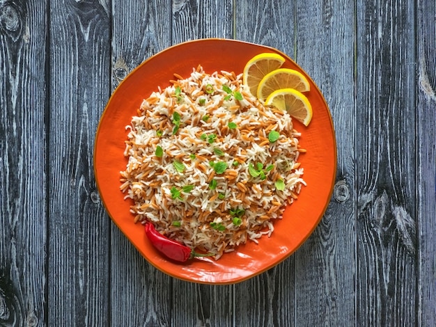 Photo turkish rice pilaf with orzo in a plate on a dark wooden background