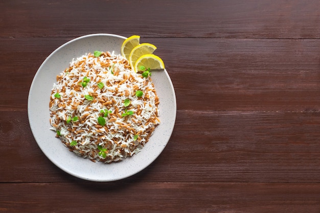 Turkish rice pilaf with orzo in a plate on a wooden background. Top view.