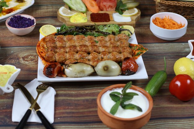 Foto cena turca allo spiedo di shish kebab con fette di verdure grigliate e salse