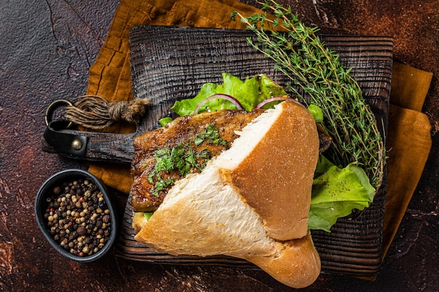 Foto cibo di strada turco panino di pesce balik ekmek con filetto di sgombro grigliato in un panino sfondo scuro vista dall'alto