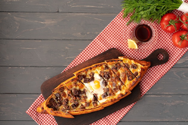 Turkish stuffed flatbread pide on gray wooden table