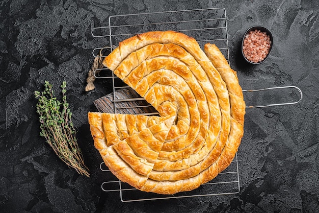 Turkish Tepsi Boregi Round Borek cheese pie on kitchen board Black background Top view