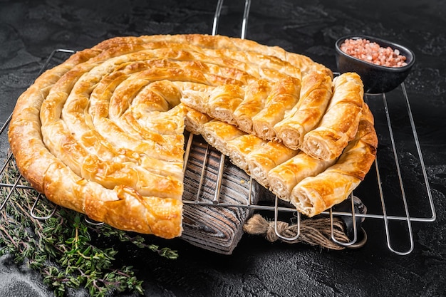 Turco tepsi boregi torta di formaggio borek rotonda su tavola da cucina sfondo nero vista dall'alto