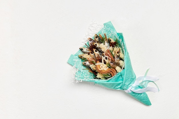 Turkoois boeket gemaakt van gedroogde vis en snacks op een witte achtergrond