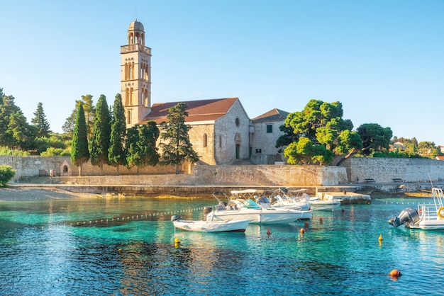 Turkoois water van de baai van de Adriatische zee op het eiland Hvar met francisciaanse klooster en boten in de regio Dalmatië, Kroatië