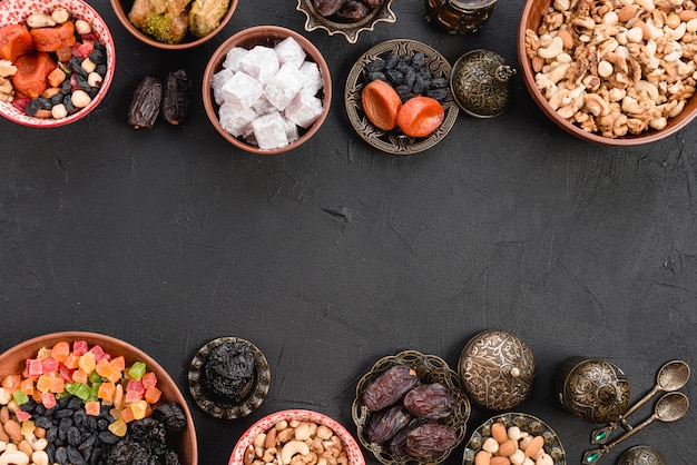 Turks fruit met gedroogde vruchten; noten; lukum en baklava op zwarte concrete achtergrond