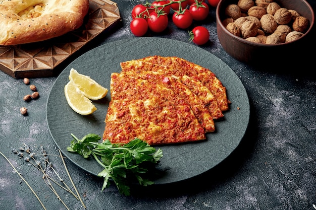 Turkse keukenschotel - pide met gehakt en tomaten op een zwarte plaat. Turkse lahmajun, close up,