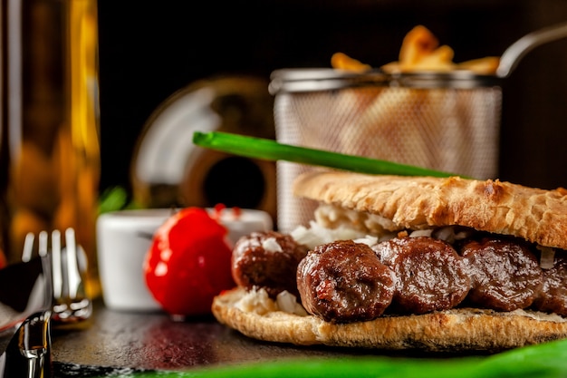 Turkse, oosterse keuken. Turkse tortilla, broodje, pitabroodje met kebab en ingelegde uitjes. Serveren in een restaurant op een zwarte lei, op houten tafel