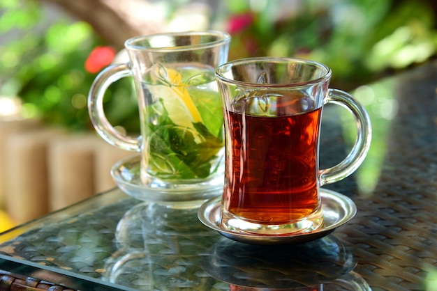 Turkse thee en muntthee met citroen in glazen bekers op glazen tafel