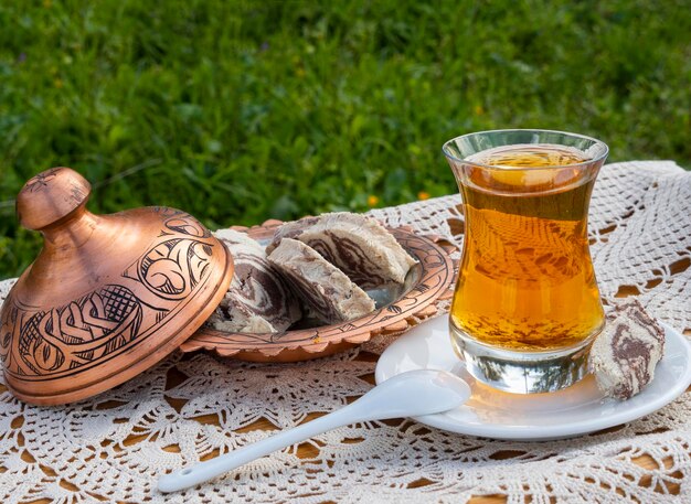 Turkse thee in een glazen beker en marmeren halva op een tafel met een handgemaakt tafelkleed en een snoepmaker