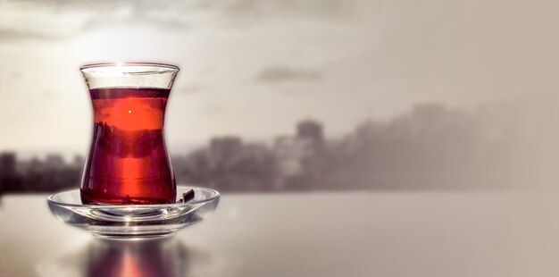 Turkse thee in glas in de vorm van armudu staat op tafel tegen de achtergrond van de natuur in contour