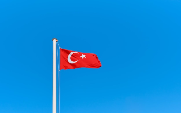 Turkse vlag op een vlaggenmast tegen een helderblauwe lucht met kopieerruimte Idee voor achtergrond of behang