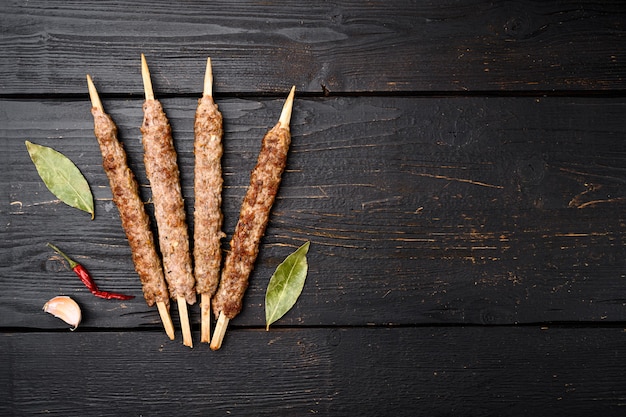 Turkse vlees kebab set, op zwarte houten tafel achtergrond, bovenaanzicht plat lag, met kopieerruimte voor tekst