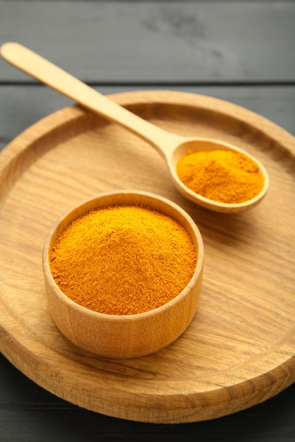 Foto turmeric curcuma in polvere su piastra di legno su sfondo nero