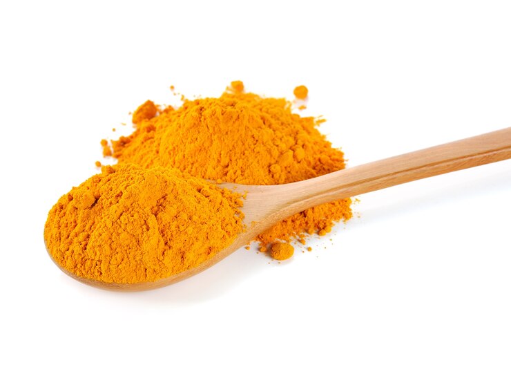 Photo turmeric (curcuma) powder on wooden spoon isolated on white background.