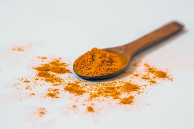 Turmeric (Curcuma) powder on wooden spoon on white background.