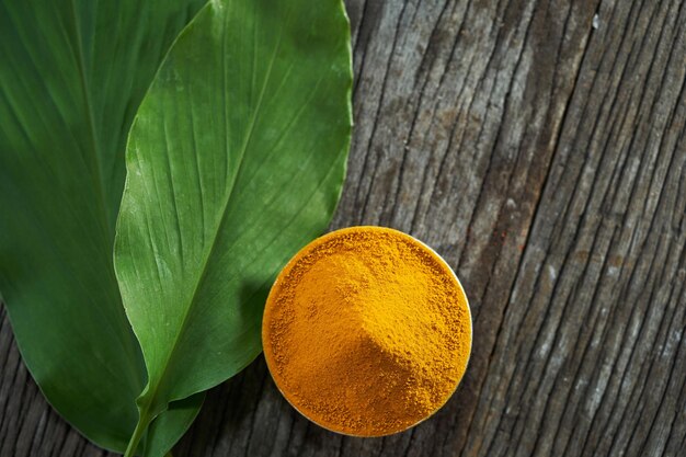 Photo turmeric curcumin powder with dry rhizome on wood background