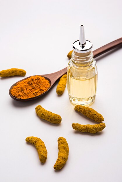 Turmeric essential oil with soap and dried Haldi sticks and powder in a wooden spoon