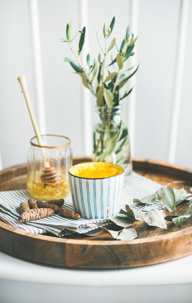 Photo turmeric latte or golden milk with honey on wooden tray