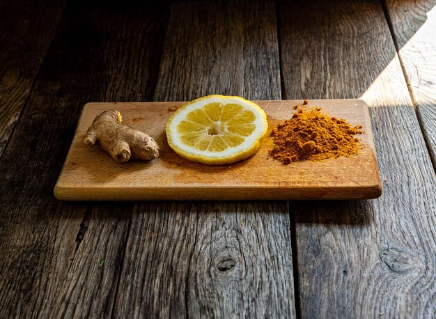 Photo turmeric and lemon on a wooden cutting board with copy space