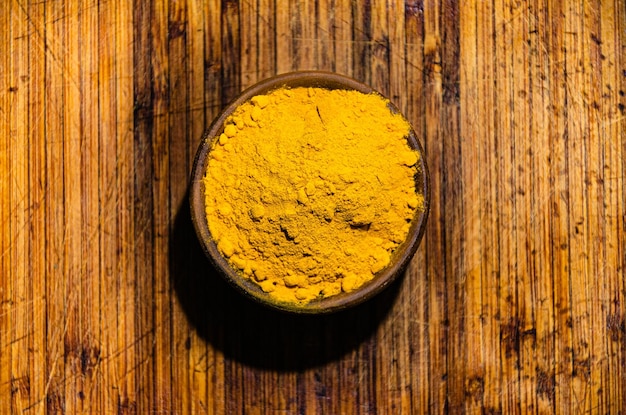 Turmeric, an oriental spice, in a wooden bowl on a wooden table.