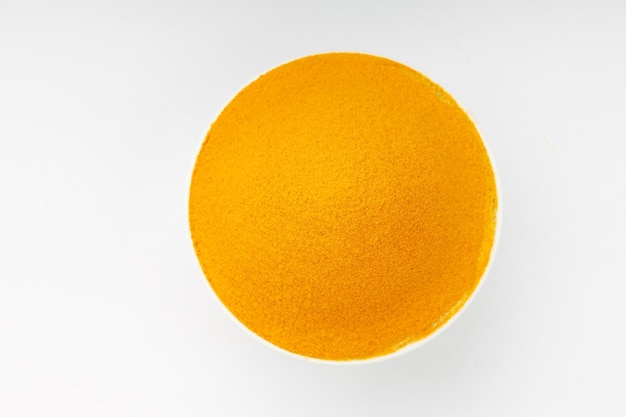 Turmeric powder arranged in a white bowl  with white texture or background