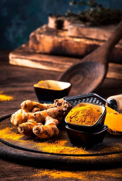 Turmeric powder and fresh turmeric on wooden background with copy space