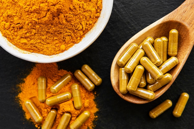 Turmeric powder and pills on black