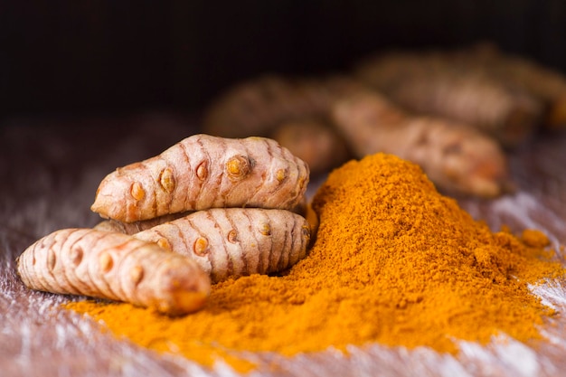 Turmeric powder and roots on wooden background