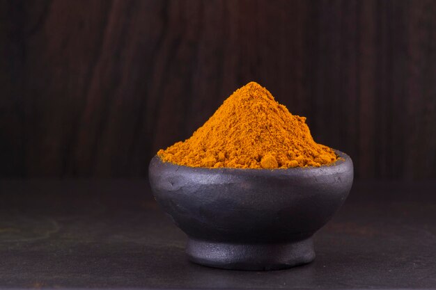 Turmeric powder and roots on wooden background