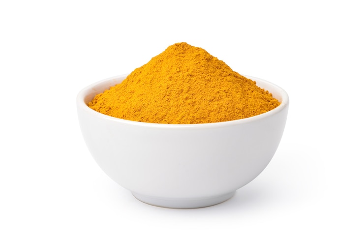 Photo turmeric powder in white bowl isolated on white