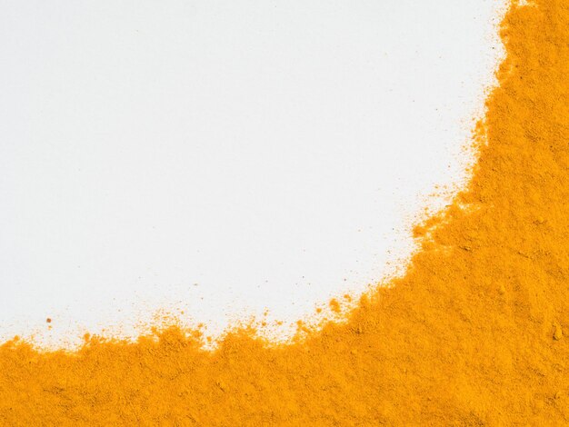 Foto polvere di curcuma su bianco con spazio per la copia