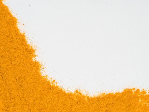 Foto polvere di curcuma su bianco con spazio per la copia