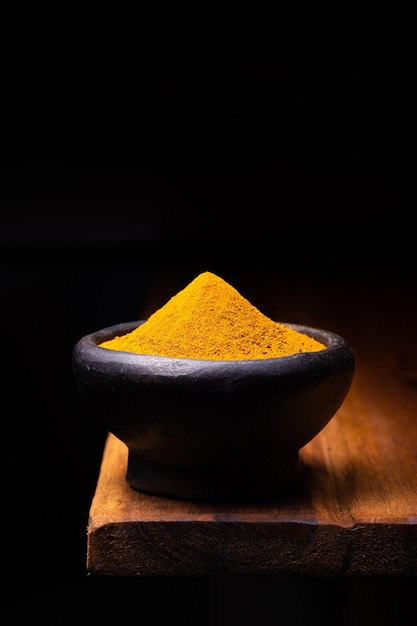 Turmeric Powder in a Wooden Spoon and Bowl