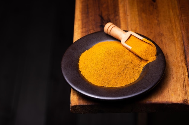 Turmeric Powder in a Wooden Spoon and Bowl