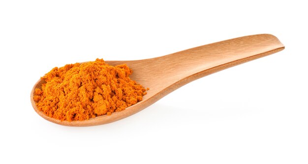 Turmeric powder in a wooden spoon on a white background