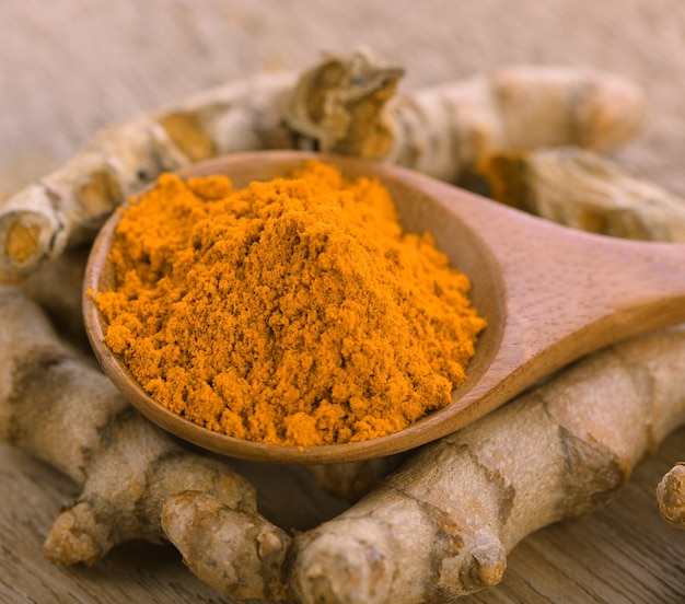 Turmeric  powder in  wooden spoon on wooden