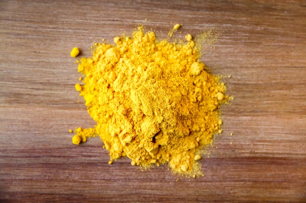 Turmeric spice powder on a wooden cutting board. Top view