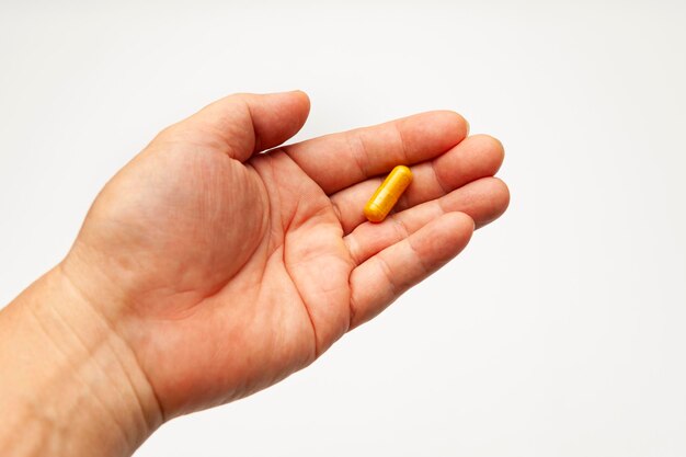 Turmeric supplement capsule in man hand isolated on white background with copy space