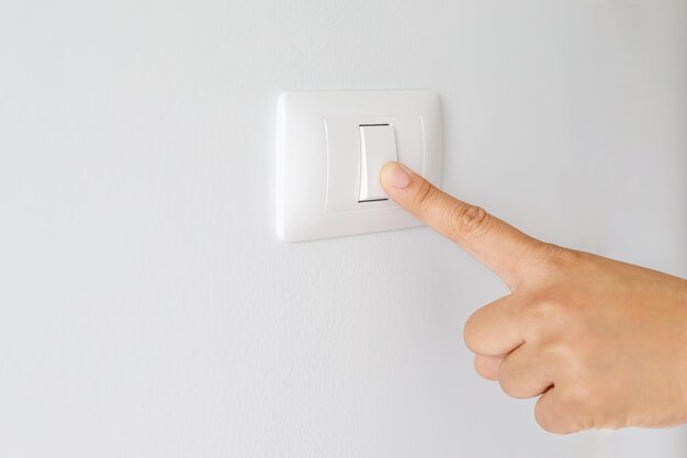 Turn off the light close up finger man hand is closing the power switch with wall at home to save energy reduce global warming