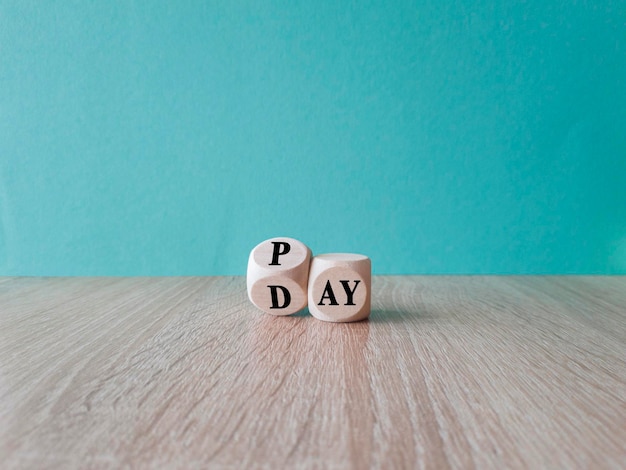 立方体を回転させ、「Pay to Day」という単語を変更します。美しい青色の背景の木製テーブル