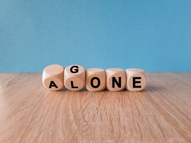 Turned a dice and changes the word gone to alone Beautiful wooden table blue background