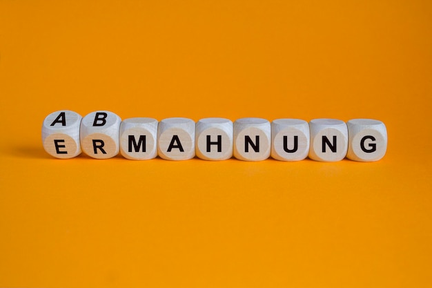 Photo turned dices and changes the german word ermahnung admonition to abmahnung dissuasion